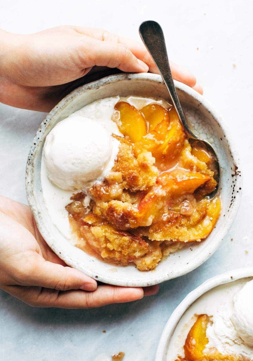 Peach cobbler in a bowl with ice cream.